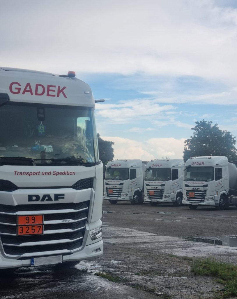 Flota pojazdów GADEK z oznaczeniami ADR zaparkowana na placu firmy – gotowość do przewozu materiałów niebezpiecznych.